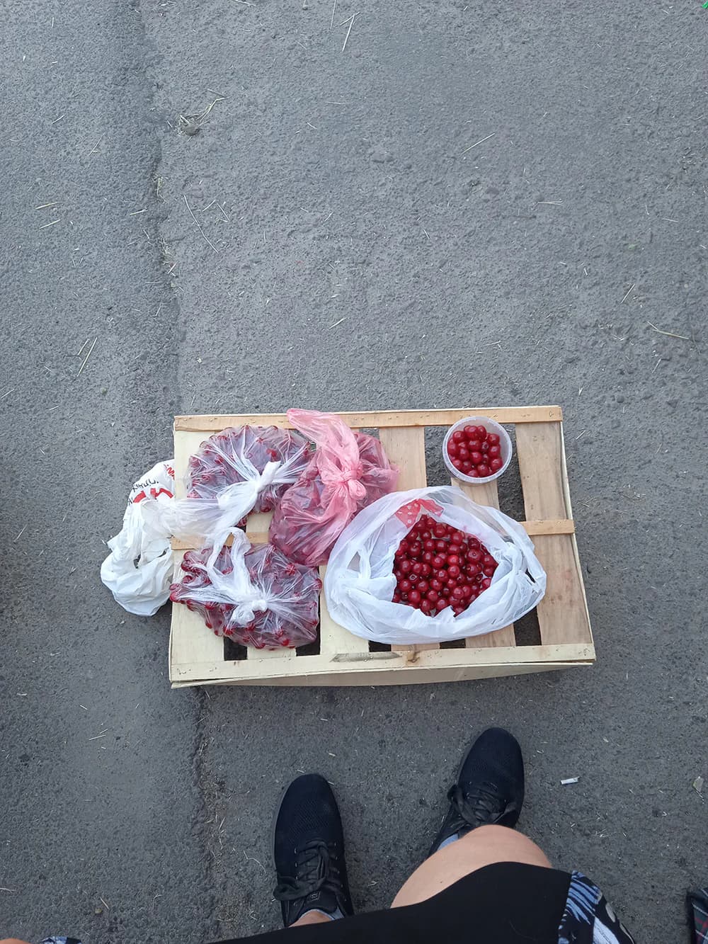 Засновниця «Маріупольського тістечка» Любов Погребняк продає вишні на стихійному ринку. Так Любов заробляла гроші, аби придбати кухонні ваги для кондитерської, після того, як була змушена залишити Маріуполь. Авторка: Любов Погребенко