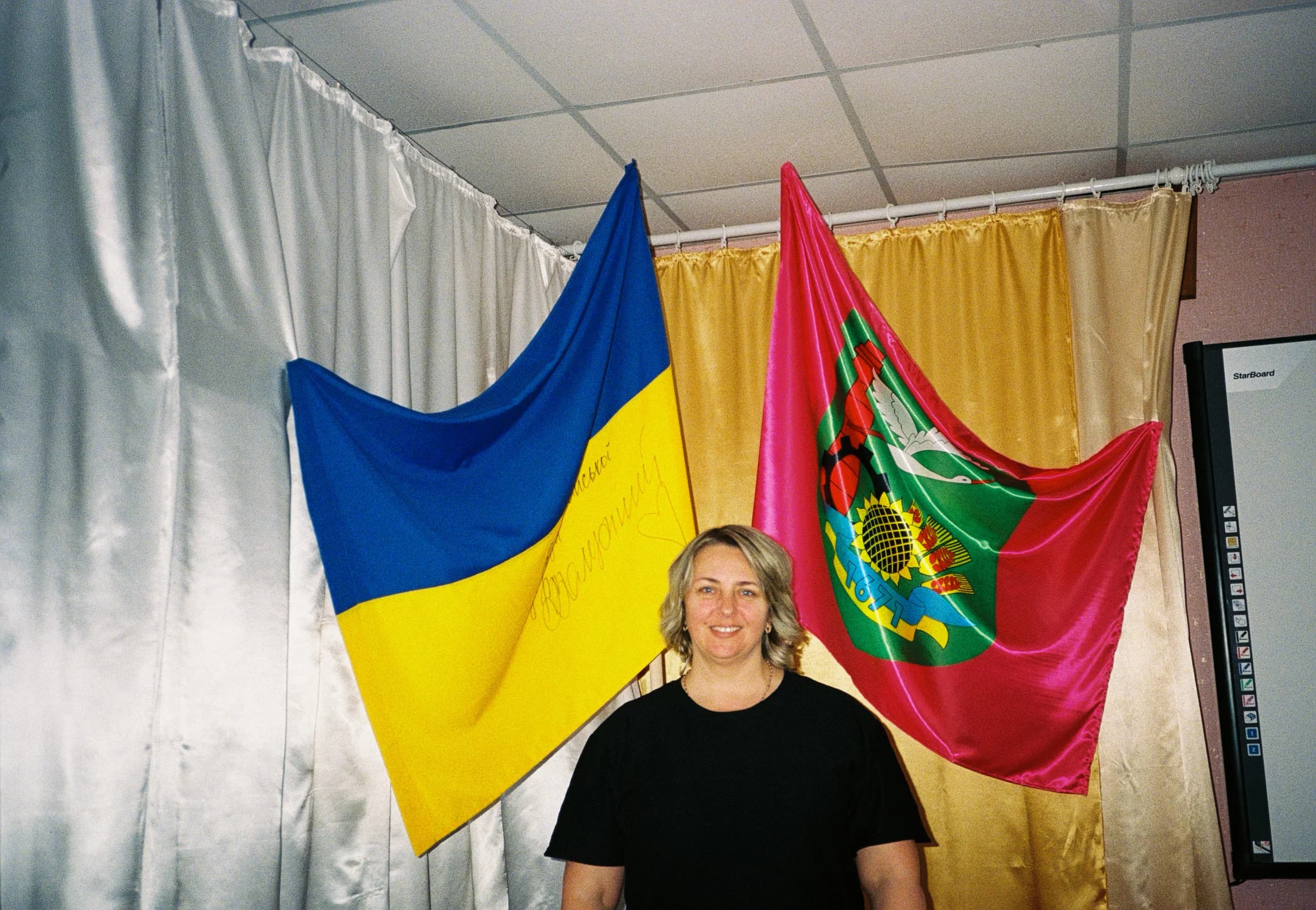 Головна спеціалістка відділу освіти Савинців Лілія Новосельска на тлі прапора громади та прапора України, підписаного Залужним